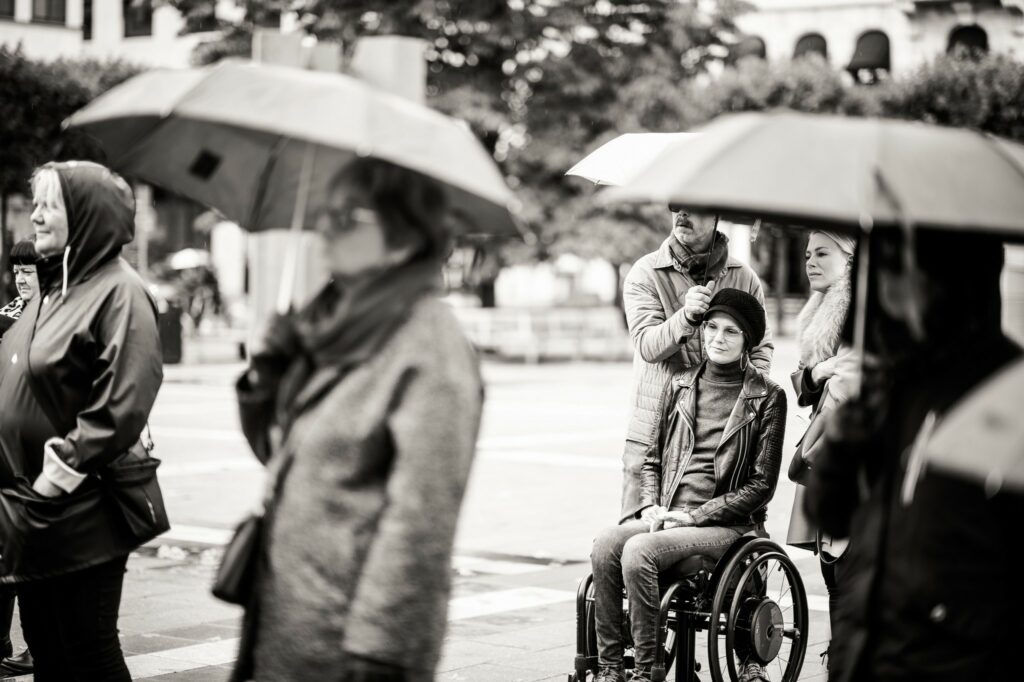Svartvitt foto. Åhörare under paraplyer, bland andra Margareta Persson Yasmin Nilson och Anna Quarnström.
